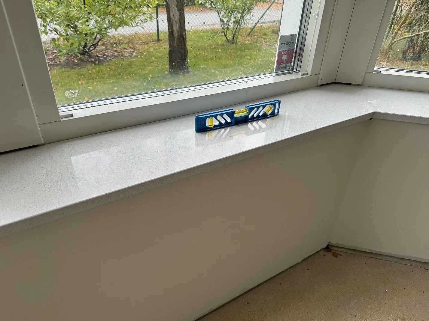 Fönsterbänk i polerad Dekton Arga med ljus ådring och vattenpass i ett burspråk i Höllviken.