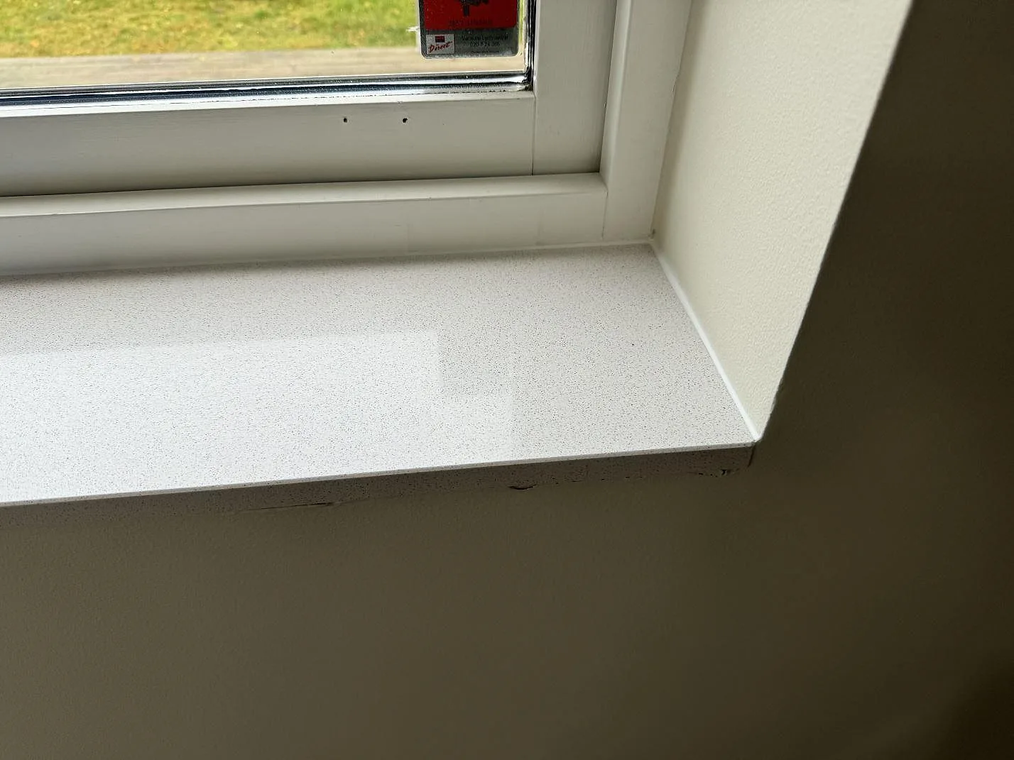 Närbild på installerad fönsterbänk i polerad Dekton Arga vid hörn och fönster i Höllviken.