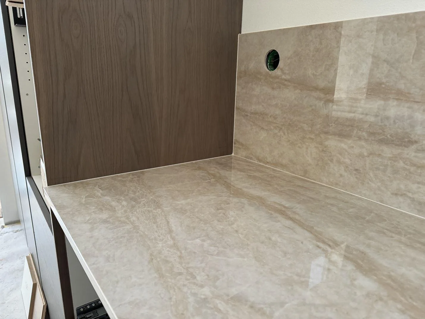 Detalj av polerad Dekton Arga bänkskiva och stänkskydd intill träpanel i ett kök i Höllviken.