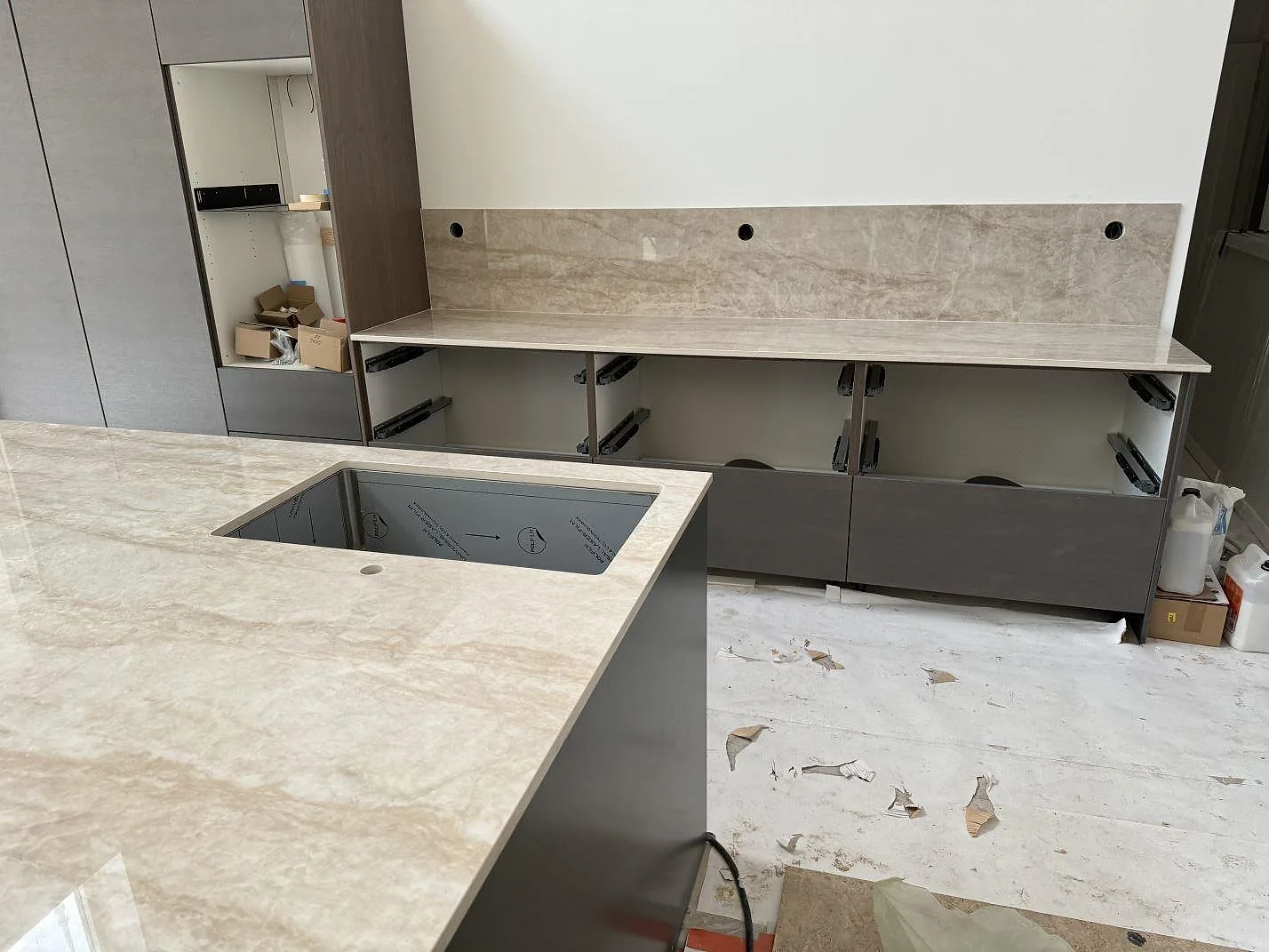 Köksö och väggbänk i polerad Dekton Arga med matchande stänkskydd och grå köksstommar i Höllviken.