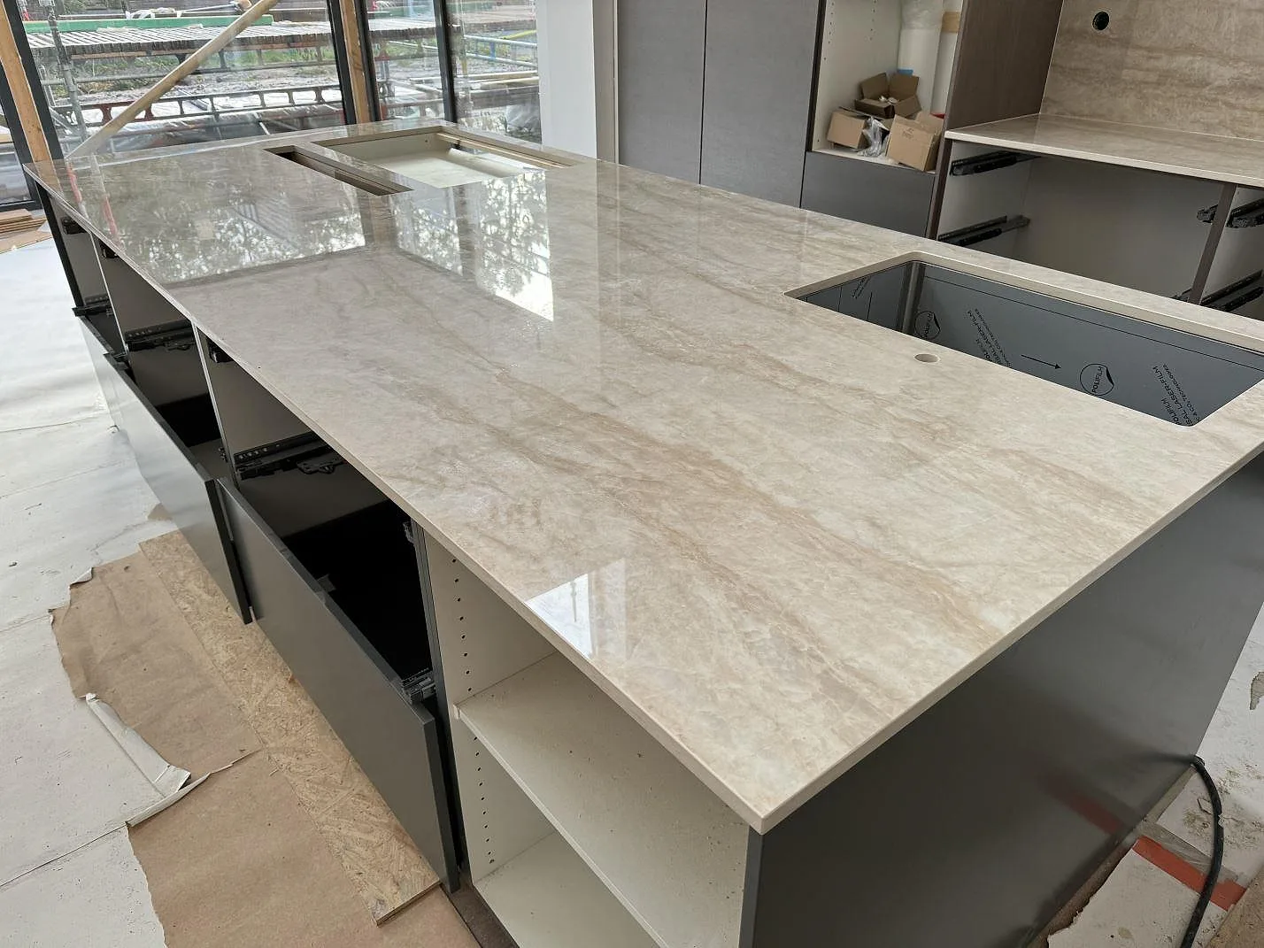 Närbild på polerad Dekton Arga på köksö med rektangulära urtag och ljus ådring i Höllviken.