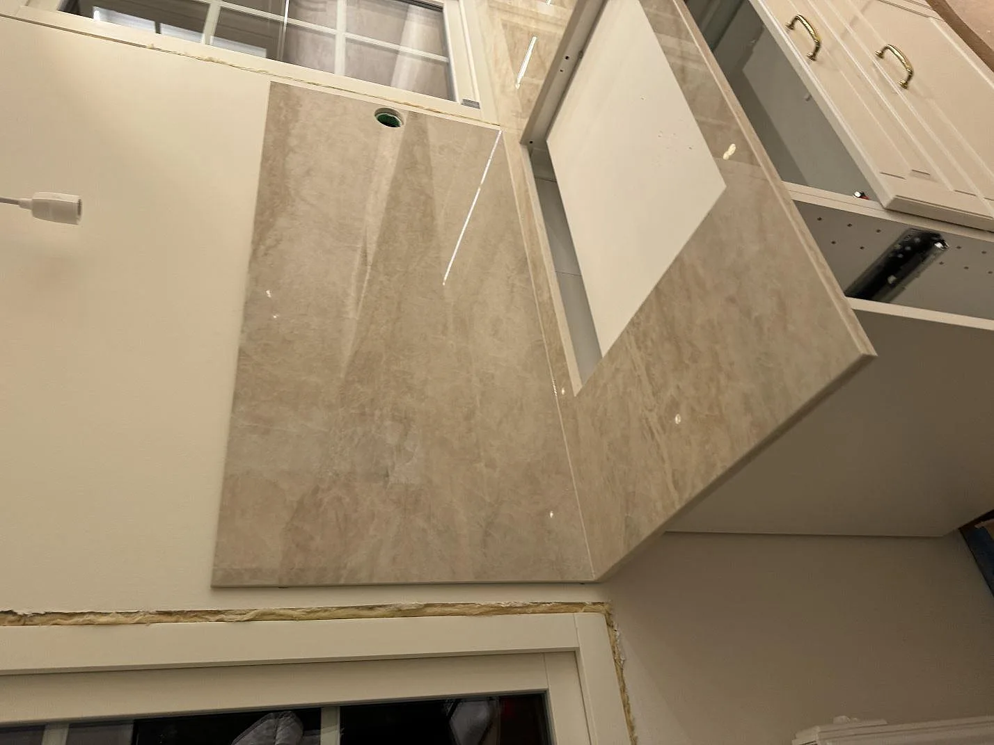 Bänkskiva i polerad Dekton Arga keramik med öppning och runt borrhål i en badrumsmiljö under montering i Höllviken.