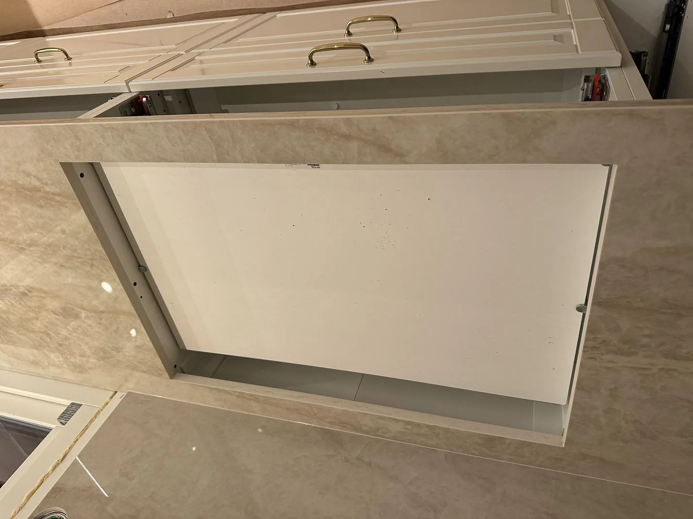 Detalj av öppning i bänkskiva av polerad Dekton Arga keramik mellan vita skåpstommar i Höllviken.