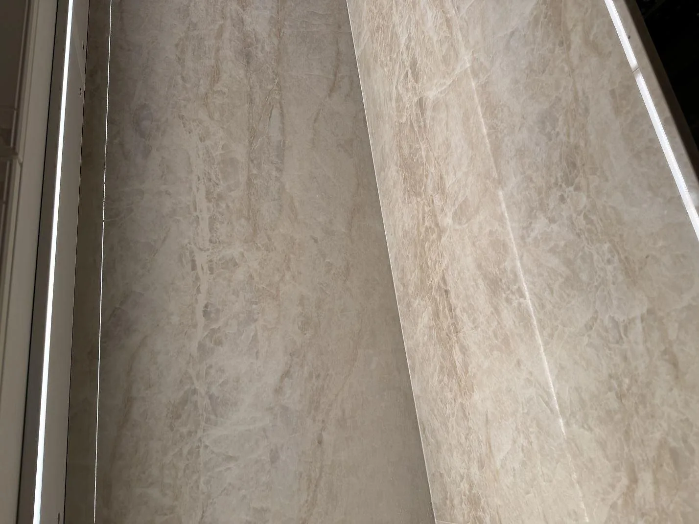 Närbild på mötet mellan bänkskiva och väggpanel i polerad Dekton Arga keramik i Höllviken.