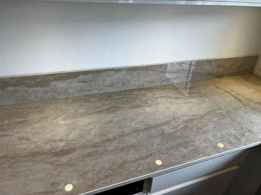 Detalj av polerad Dekton Arga bänkskiva med matchande stänkskydd och reflekterande yta i Hörby.