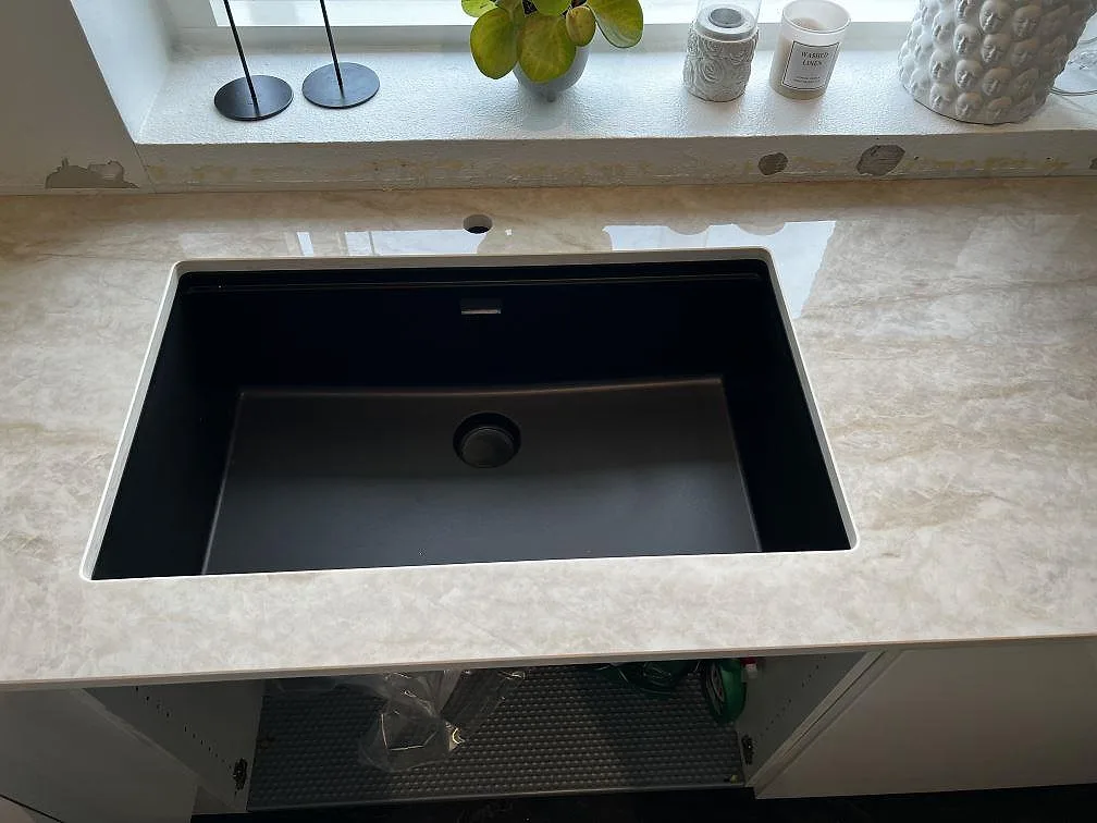 Närbild på svart underlimmad diskho i polerad Dekton Arga bänkskiva med låg stänkkant i Hörby.
