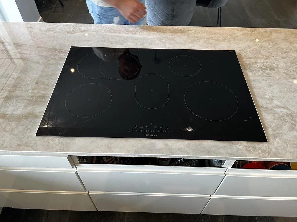 Köksö med svart induktionshäll infälld i polerad Dekton Arga keramik i ett kök i Hörby.