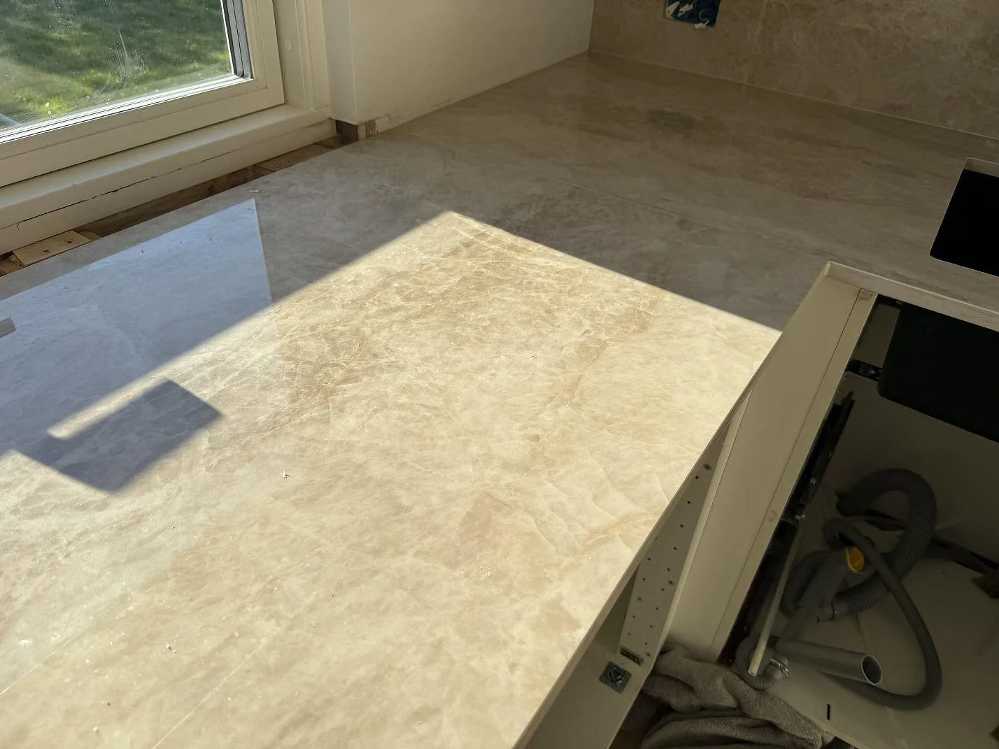 Dekton Arga som polerad keramikbänkskiva och väggdel vid hällzonen, med varm beige ådring i Hørsholm.
