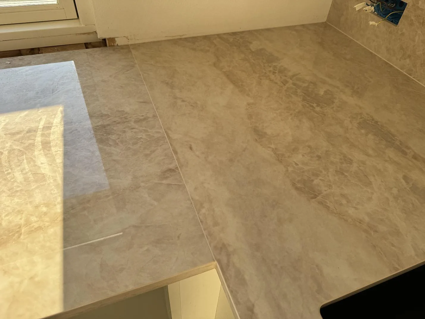 Detalj av polerad Dekton Arga vid hörn och väggbeklädnad, med synlig ådring och hällkant i ett kök i Hørsholm.