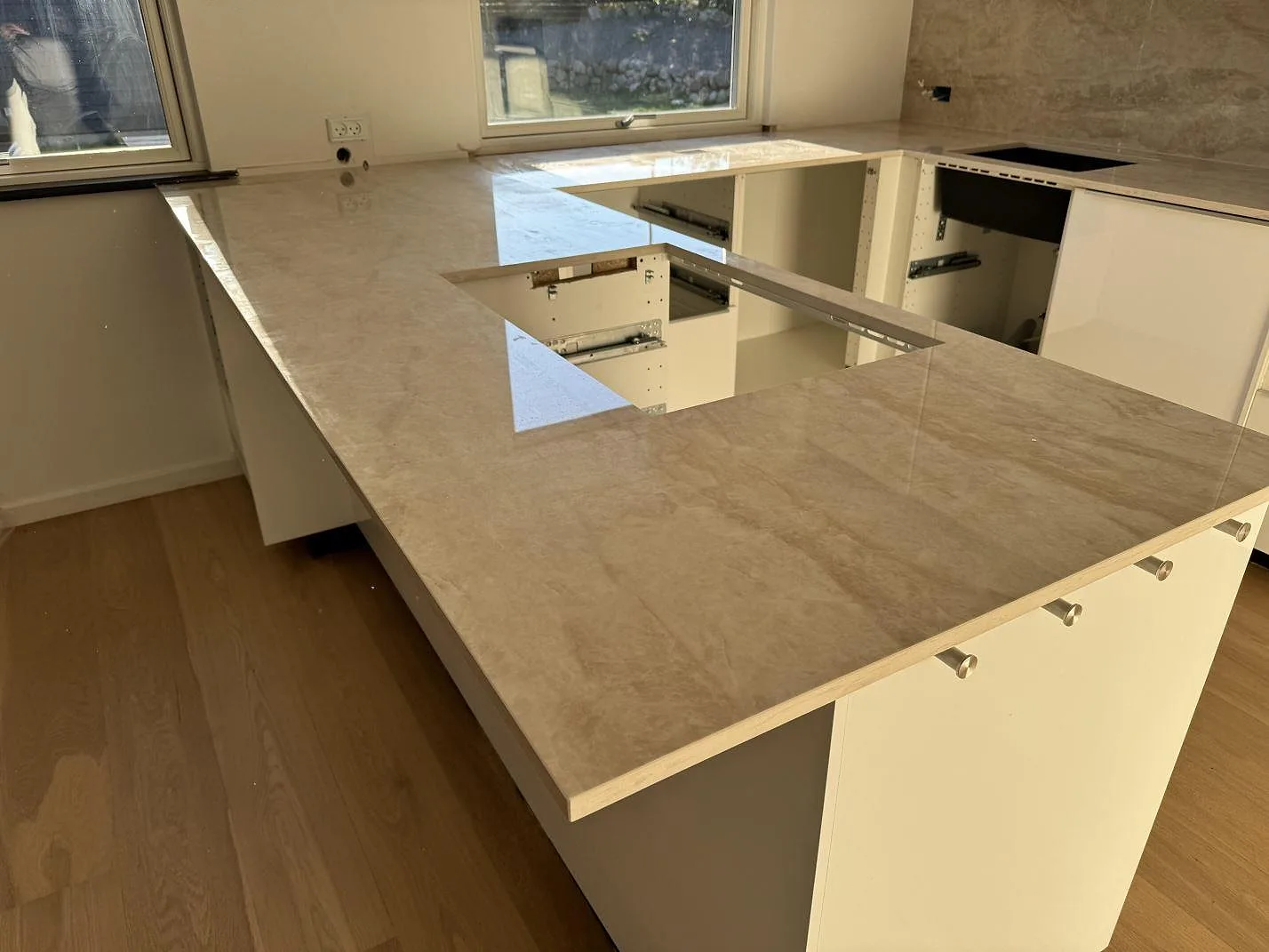 Stor köksö och köksbänkskiva i Dekton Arga, polerad keramik, med rektangulärt urtag och hällzon i ett kök i Hørsholm.