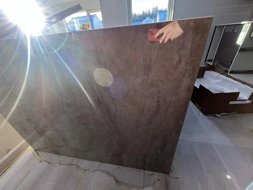 Vertikal sida på köksö i polerad Dekton Arga keramik med tydlig stenådring under montering i Huddinge.