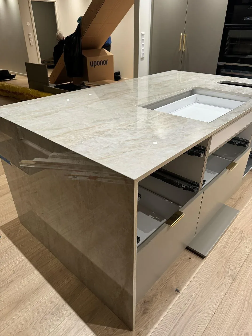 Köksö i polerad Dekton Arga med vattenfallsida, öppen stomme och ljus ådring i ett kök i Hunnebostrand.