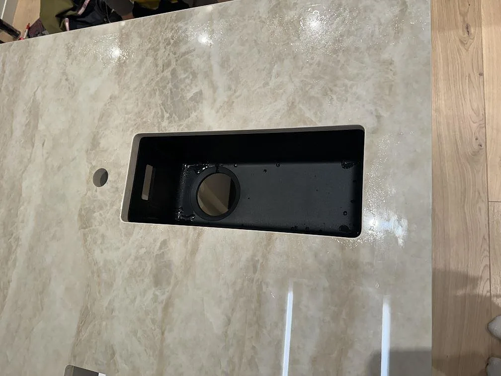 Detalj av rektangulärt urtag och rund håltagning i polerad Dekton Arga på en köksö i Hunnebostrand.
