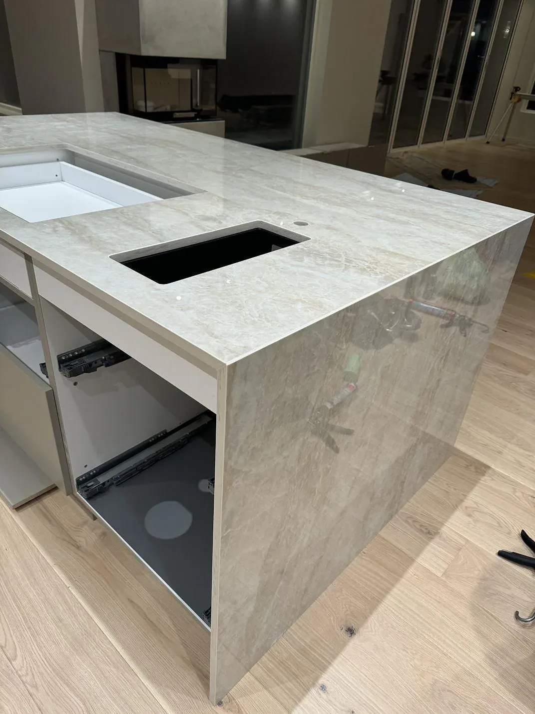 Sidovy av köksö i polerad Dekton Arga med vattenfallsida, diskhoöppning och rektangulärt urtag i Hunnebostrand.