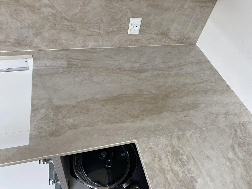 Hörnsektion i polerad Dekton Arga med synlig öppning i bänken och stänkskydd i Hvidovre.