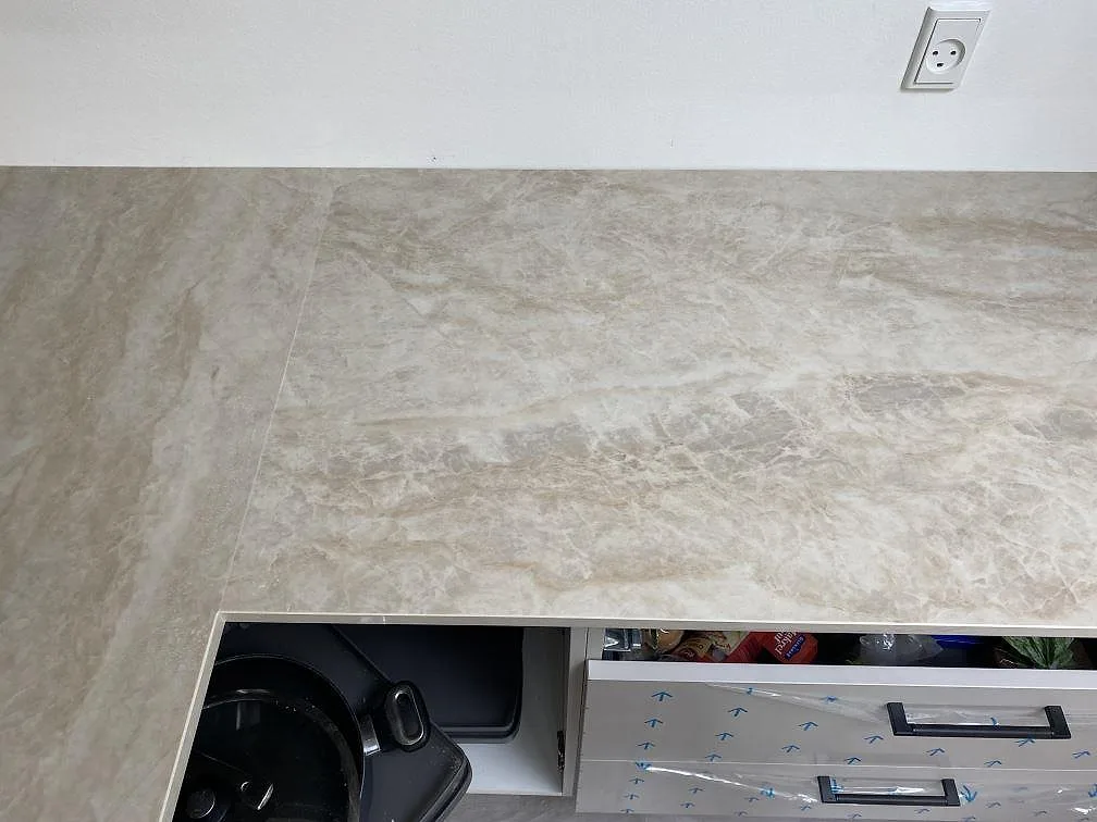 Köksbänkskiva i polerad Dekton Arga längs vägg, med öppna lådstommar och varm ådring i Hvidovre.