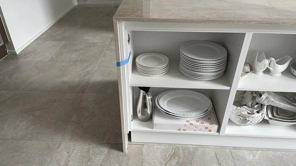 Detalj av köksö med polerad Dekton Arga keramik, öppen vit stomme och stenklädd gavel i Hvidovre.