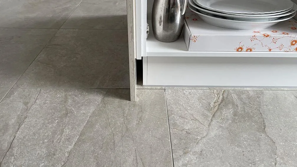 Detalj av stenklädd köksö i polerad Dekton Arga keramik där gaveln möter golvet i Hvidovre.