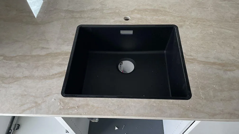 Närbild av svart diskho i bänkskiva av polerad Dekton Arga keramik med varm ådring i Hvidovre.