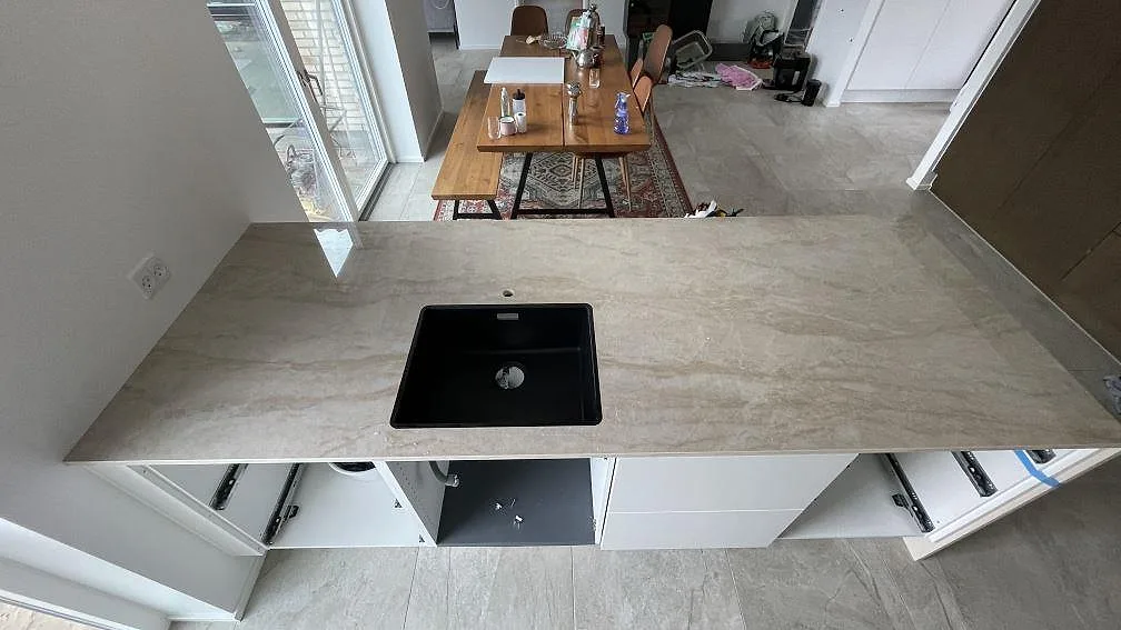 Bänkskiva i polerad Dekton Arga keramik med svart diskho och kranhål i ett kök i Hvidovre.