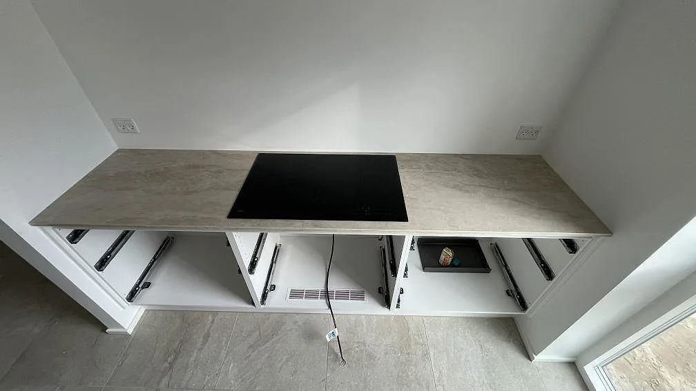 Rak köksbänk i polerad Dekton Arga keramik med svart häll och öppna stommar i Hvidovre.