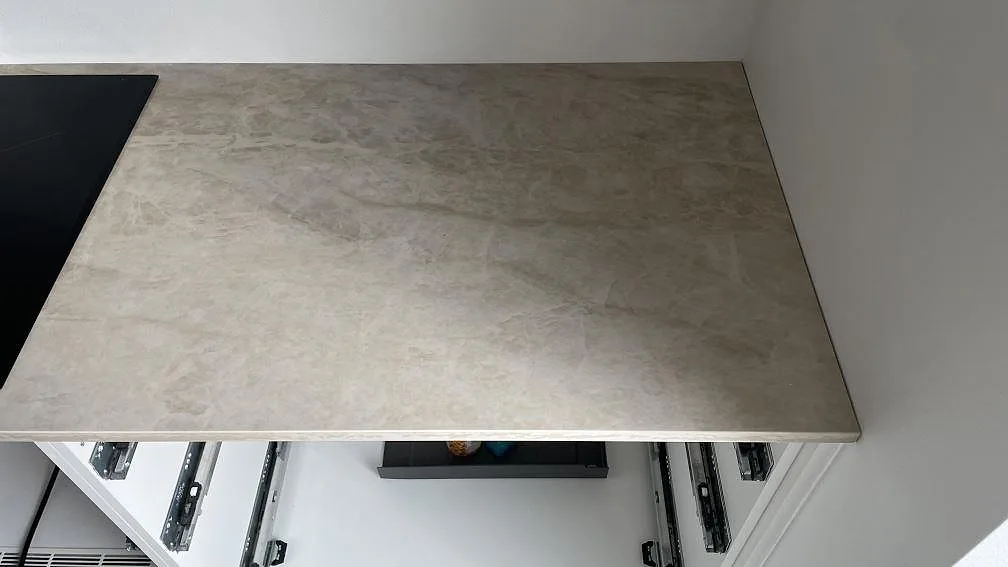 Närbild av polerad Dekton Arga keramik bredvid svart häll, med synlig ådring i ett kök i Hvidovre.