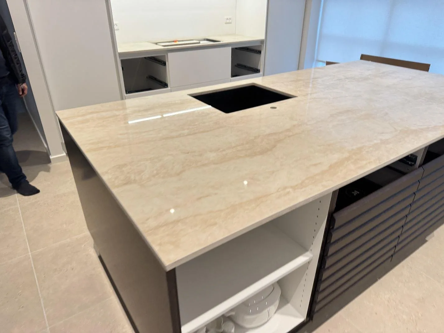 Polerad köksö i Dekton Arga med stor arbetsyta, svart diskho och öppna stommar i ett kök under montering i Hvidovre.