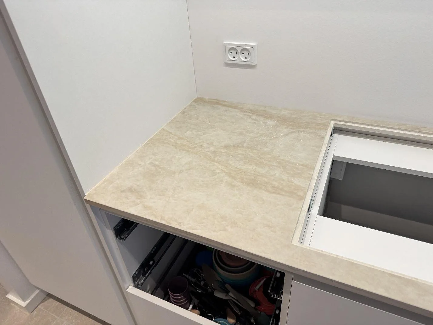 Detalj av polerad Dekton Arga bänkskiva med förberedd hällöppning och öppna lådor i ett kök i Hvidovre.
