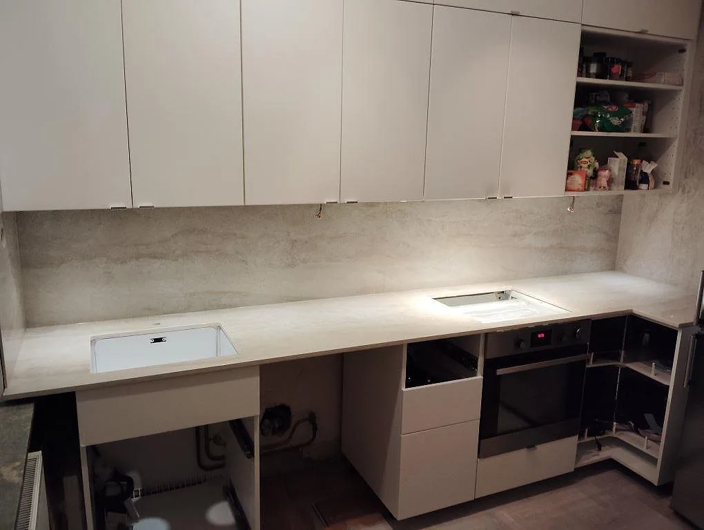 Polerad köksbänkskiva i Dekton Arga med ljus stänkbeklädnad, diskho och häll under montering i ett kök i Johanneshov.