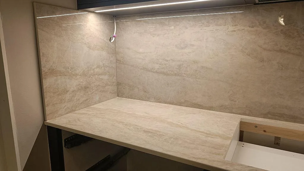 Hörnparti av köksbänkskiva i Dekton Arga med heltäckande stänkskydd under montering i ett kök i Kalmar.