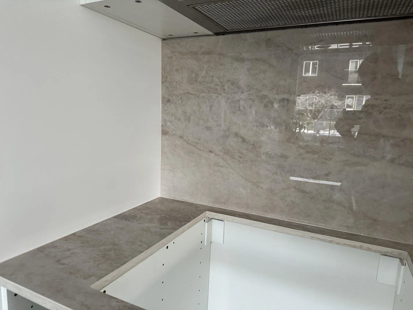 Köksbänkskiva i polerad Dekton Arga keramik med blank väggbeklädnad över vita köksstommar i Kalmar.