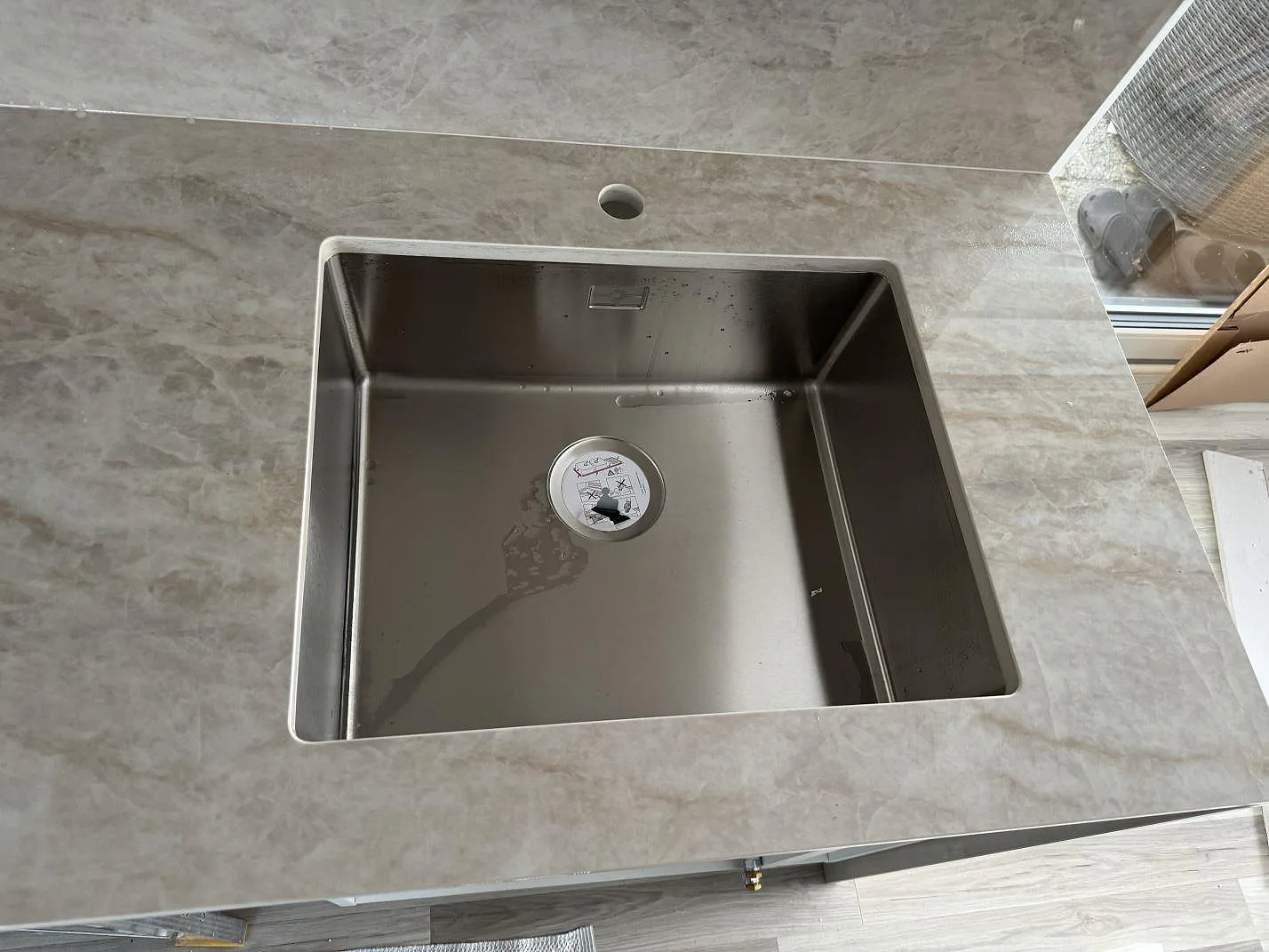 Närbild på underlimmad rostfri diskho i polerad Dekton Arga med kranhål och gråbeige ådring i Kalmar.