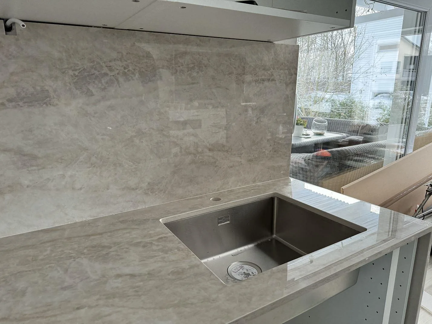 Polerad Dekton Arga bänkskiva med underlimmad rostfri diskho och hög väggbeklädnad i ett kök i Kalmar.