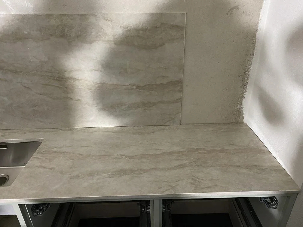 Höger bänkrad i polerad Dekton Arga med ådrad yta och 12 mm stänkskydd i ett kök under montering i Kareby.