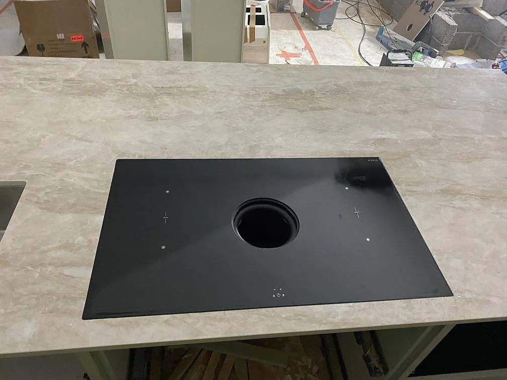 Närbild på köksö i polerad Dekton Arga med svart häll och ljus beigegrå ådring i Kareby.