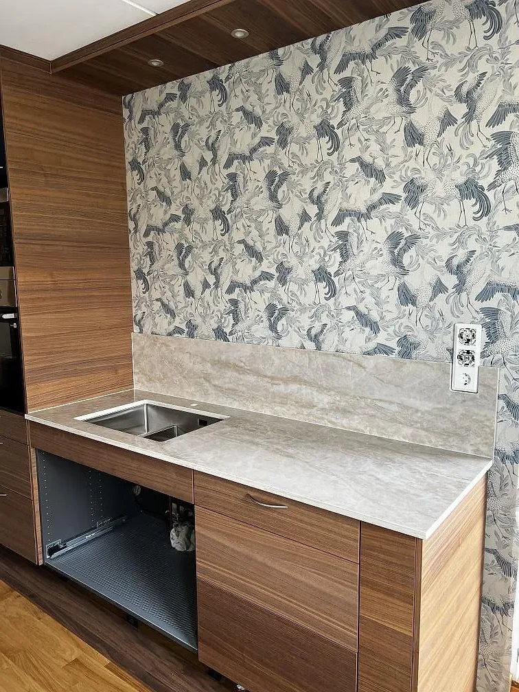 Polerad Dekton Arga som stänkdetalj och bänkyta vid valnötsfärgad träinredning i Karlskrona.