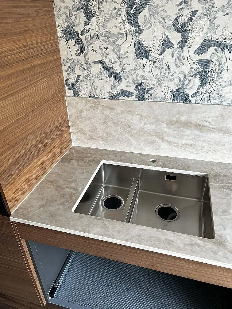 Närbild av polerad Dekton Arga vid synlig diskho och matchande stänkdetalj mot mönstrad vägg i Karlskrona.