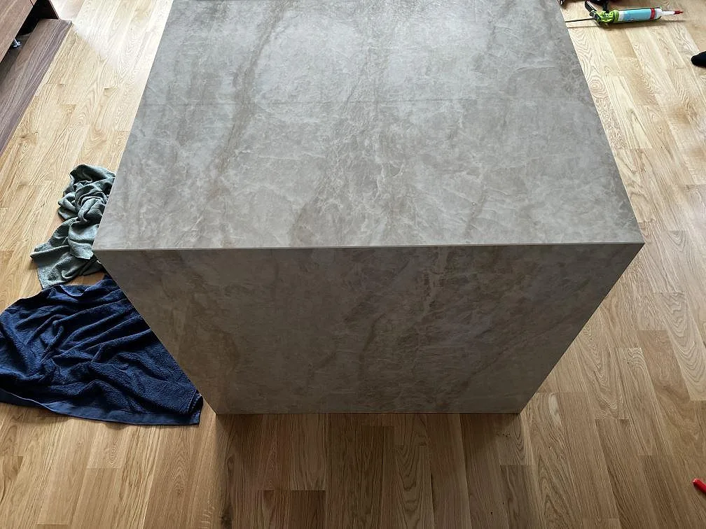 Front och ovansida på köksö i polerad Dekton Arga keramik med grå travertinlik ådring i Karlskrona.