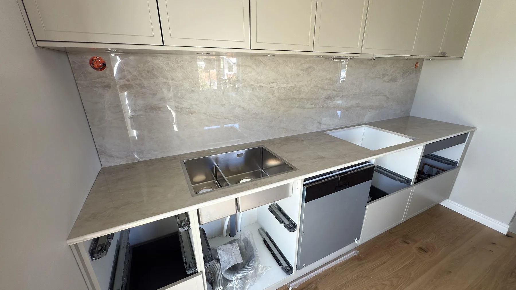 Köksbänkskiva i Dekton Arga, polerad keramik i cremebeige med marmorliknande ådring, med underlimmad rostfri diskho och heltäckande polerat stänkskydd i ett kök i Karlstad.