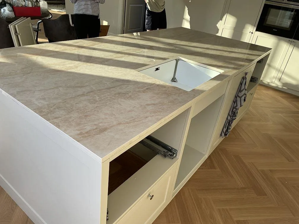 Närbild på köksö i 20 mm polerad Dekton Arga med underlimmad diskho och vita stommar i Kastrup.