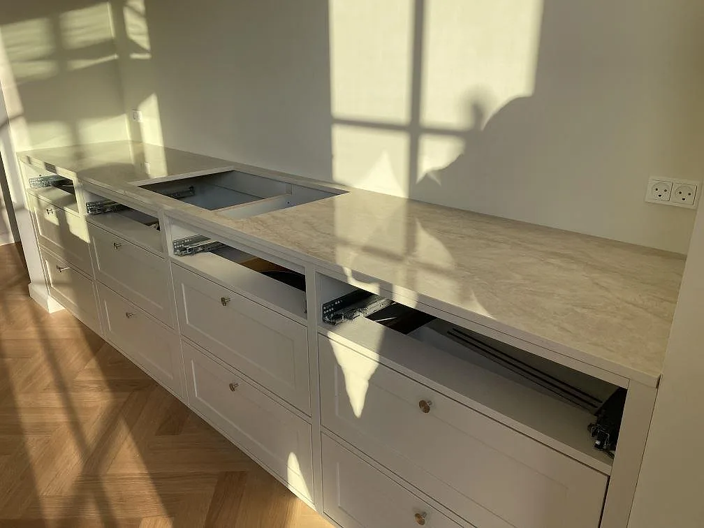 Bakre köksbänk i polerad Dekton Arga med öppning för häll och vita lådsektioner i Kastrup.