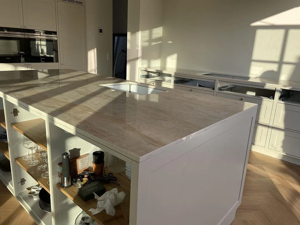 Stor köksö med polerad köksbänkskiva i Dekton Arga, 20 mm keramik, under montering i ett kök i Kastrup.