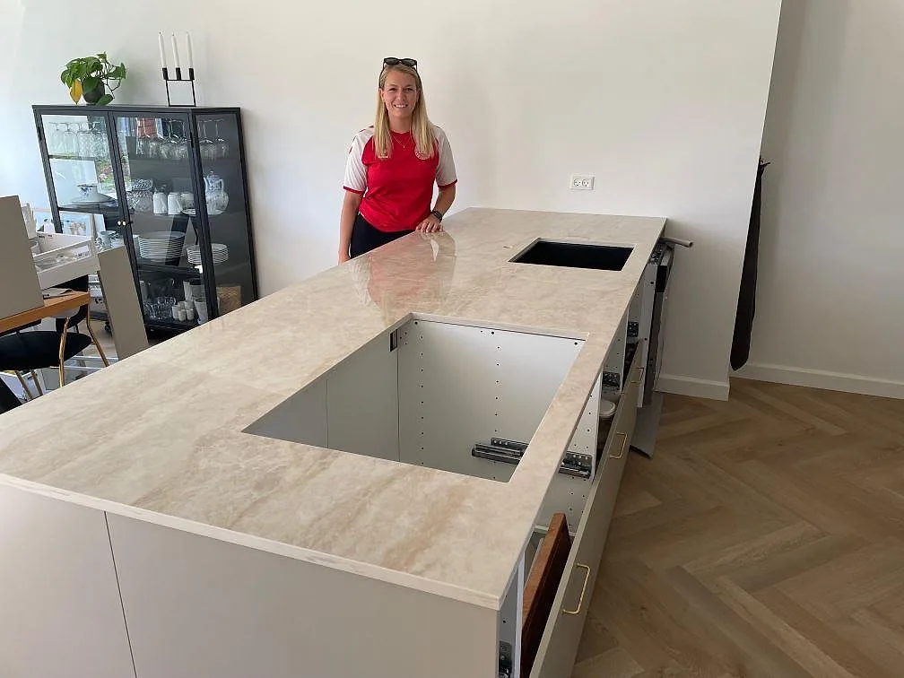 Köksbänkskiva i polerad Dekton Arga, keramik med trätonad ådring, monterad på köksö och halvö i ett kök i Kastrup.