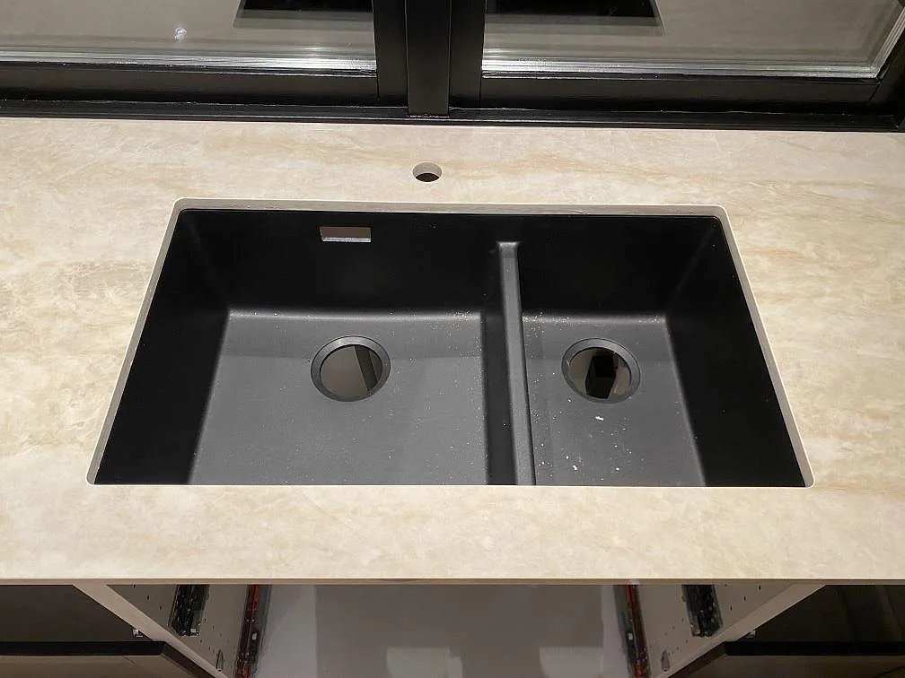 Underlimmad dubbelho i mörk antracitkomposit i en köksbänk av krämvit Dekton Arga, polerad keramik, kök i Katrineholm.