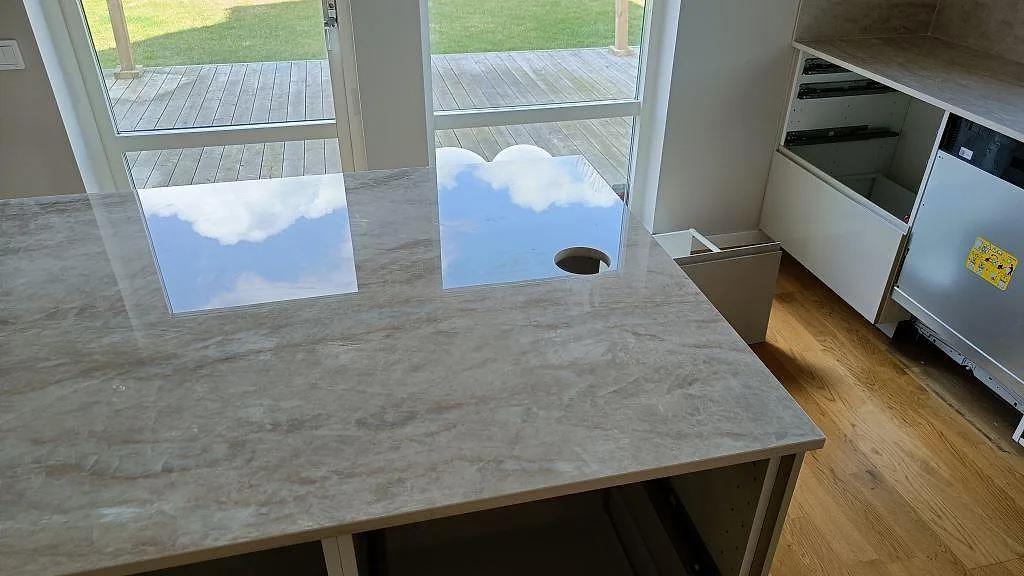 Köksö i polerad Dekton Arga med håltagning och öppna stommar under montering i Klågerup.