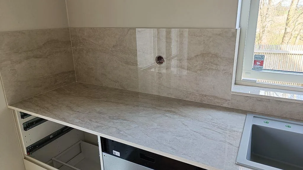 Arbetsbänk och stänkskydd i polerad Dekton Arga vid diskbänken i köket i Klågerup.