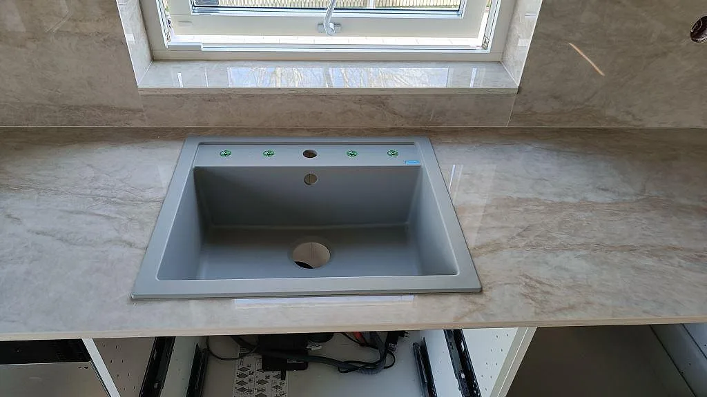 Grå underlimmad diskho i köksbänkskiva av polerad Dekton Arga med stänkskydd i Klågerup.