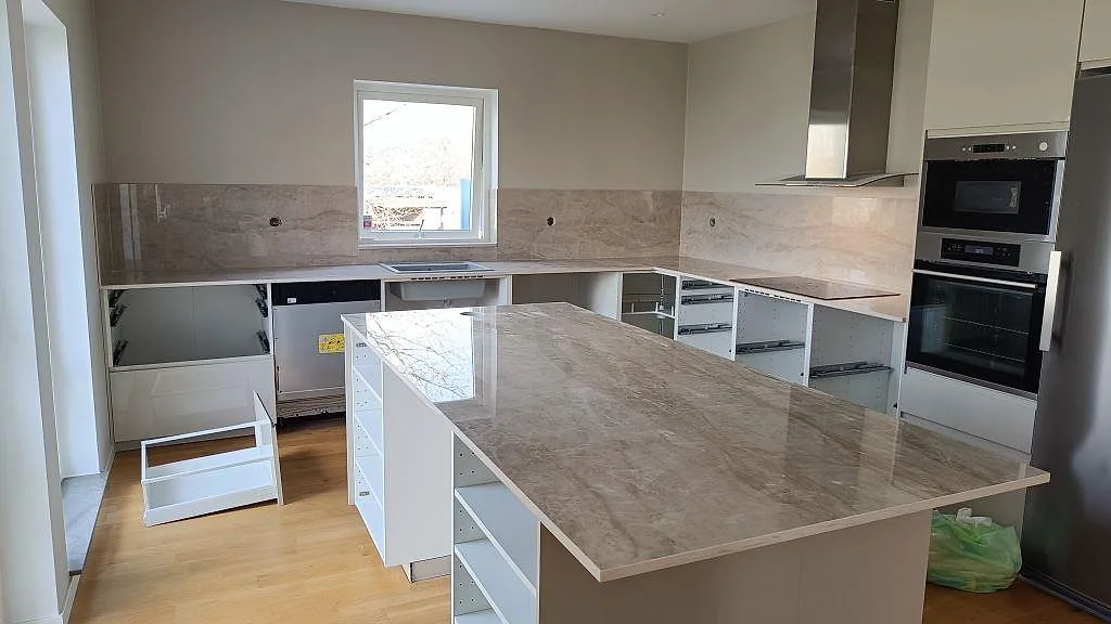Köksbänkskiva i polerad Dekton Arga med stor köksö, arbetsytor och stänkskydd i ett kök i Klågerup.