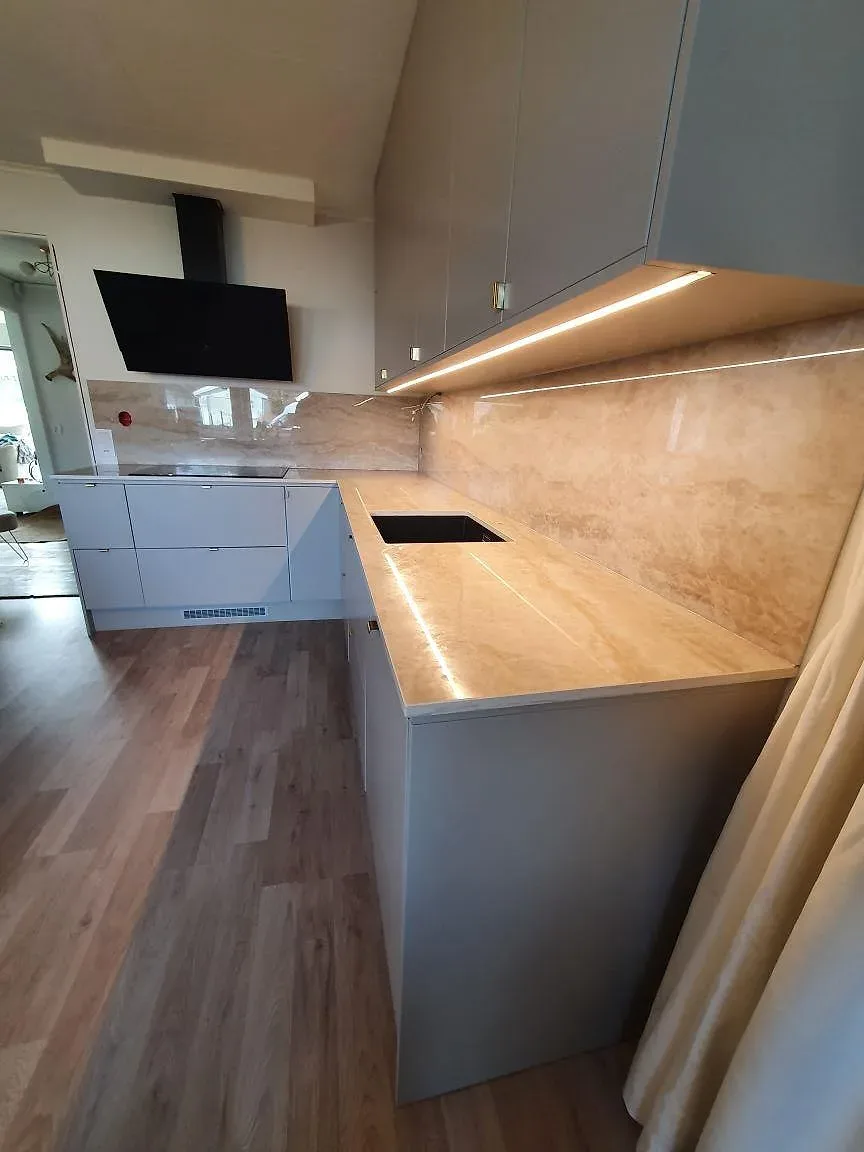 Detaljbild av polerad Dekton Arga i kök med diskhodel, häll och upplyst stänkskydd i Knutby.