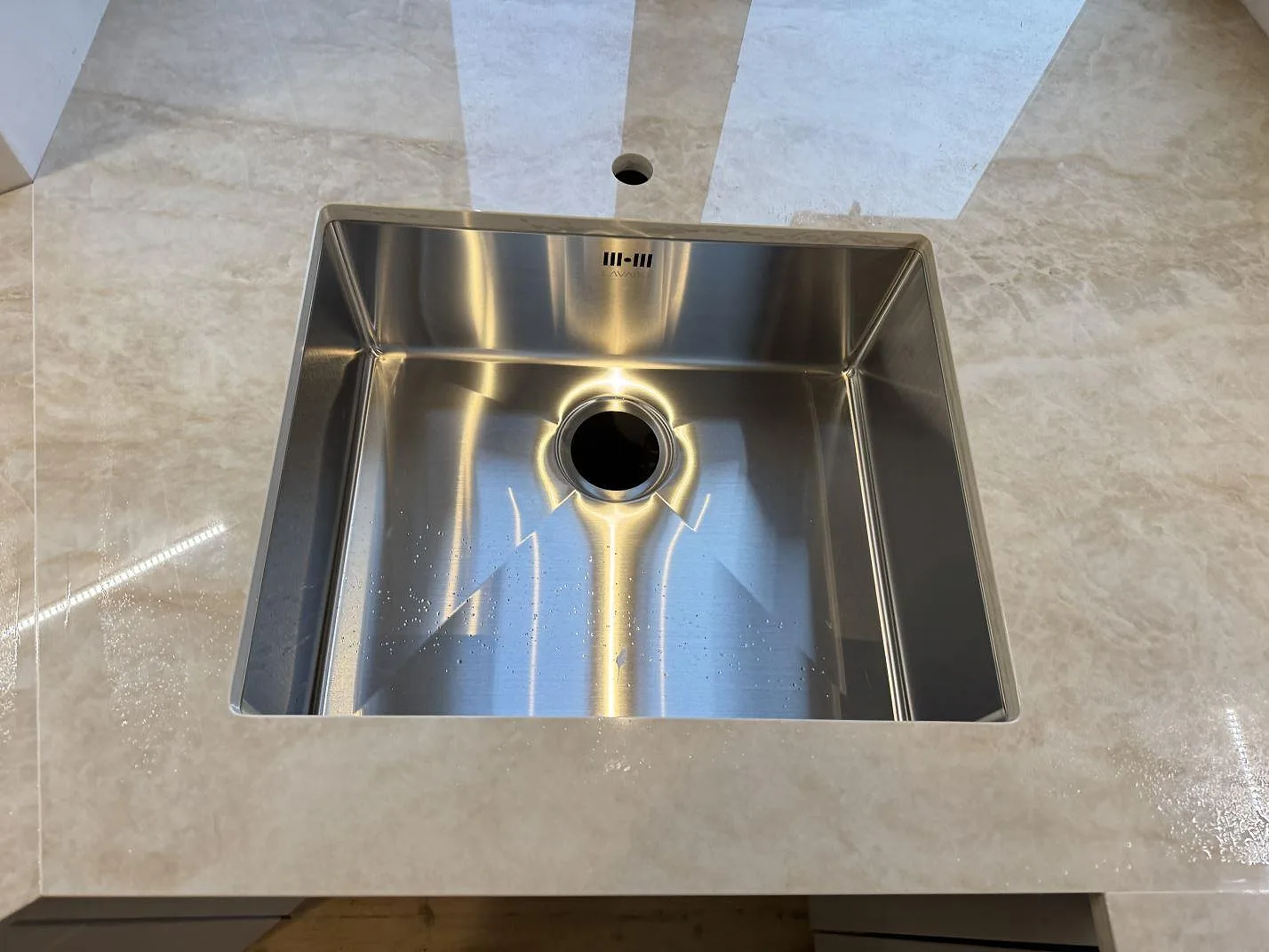 Närbild på rostfri diskho och blandarhål i polerad Dekton Arga köksbänkskiva med ljus ådring i København N.
